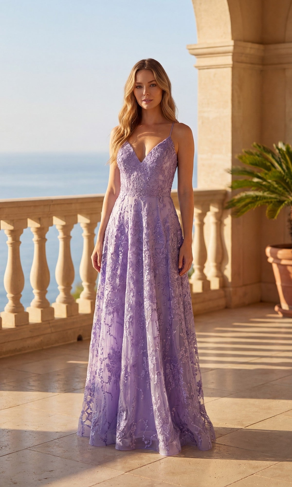 On a terrace overlooking the sea, a woman wears the Chicas C804 Long Prom Dress in lavender, featuring a V-neck, thin straps, and delicate floral lace embroidery.